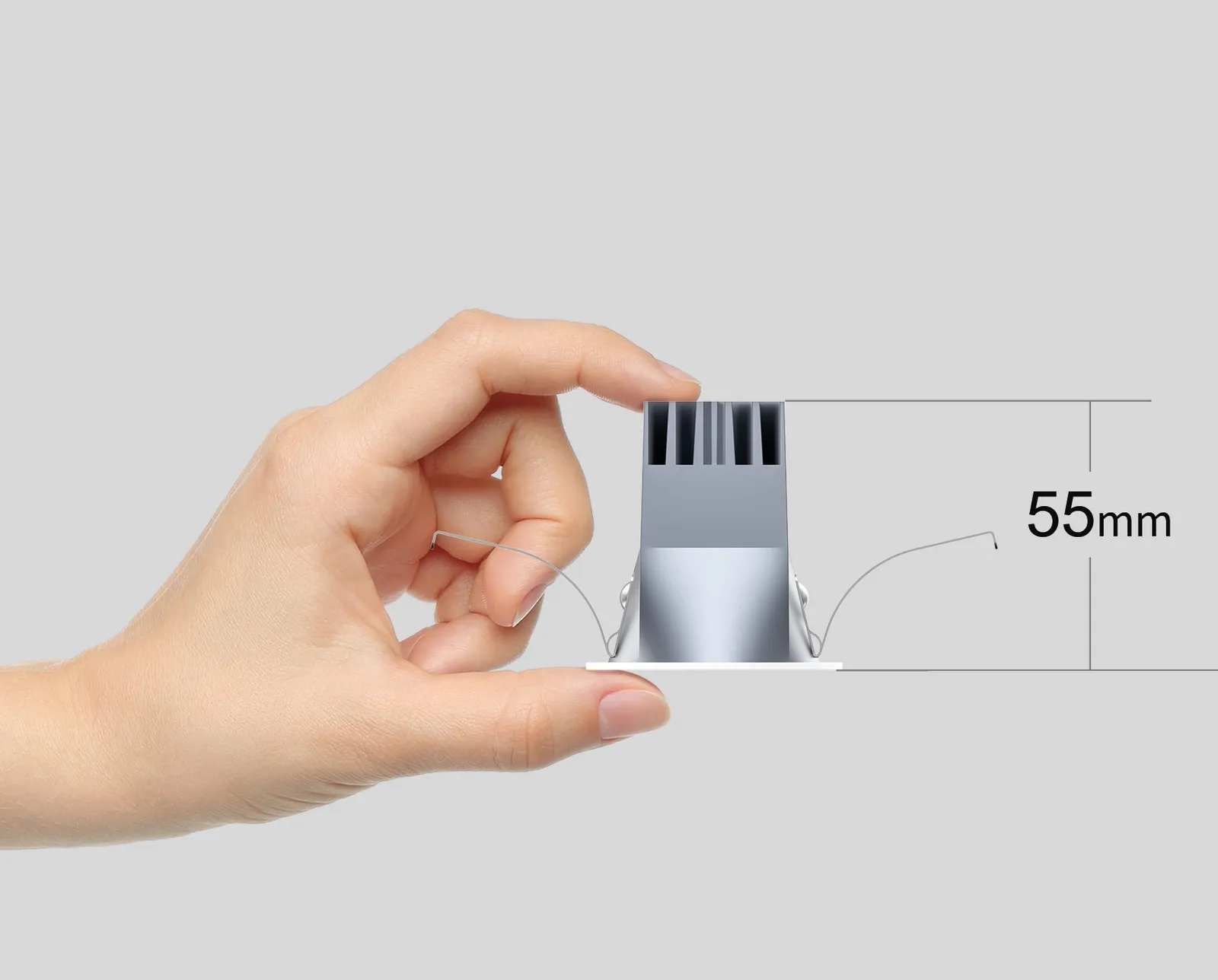 A Havious XS spotlight held between finger and thumb, marked 55 mm high