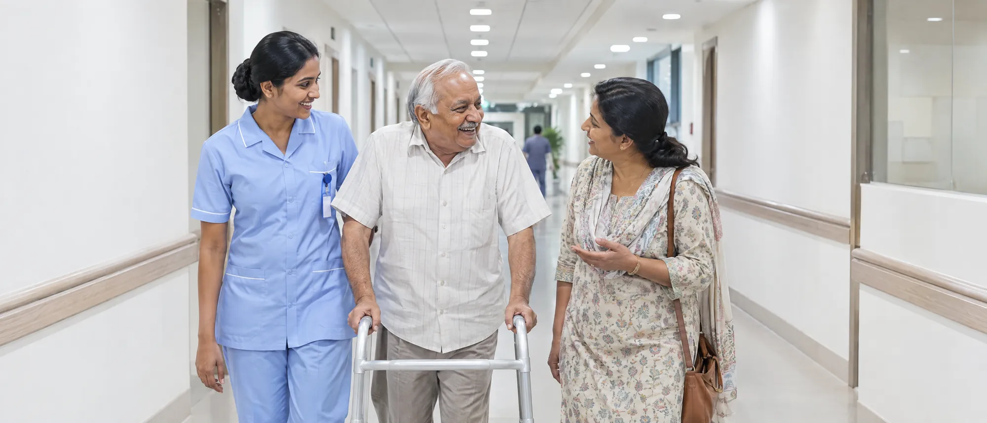 A nurse walks beside an elderly patient and his daughter along a bright hospital corridor
